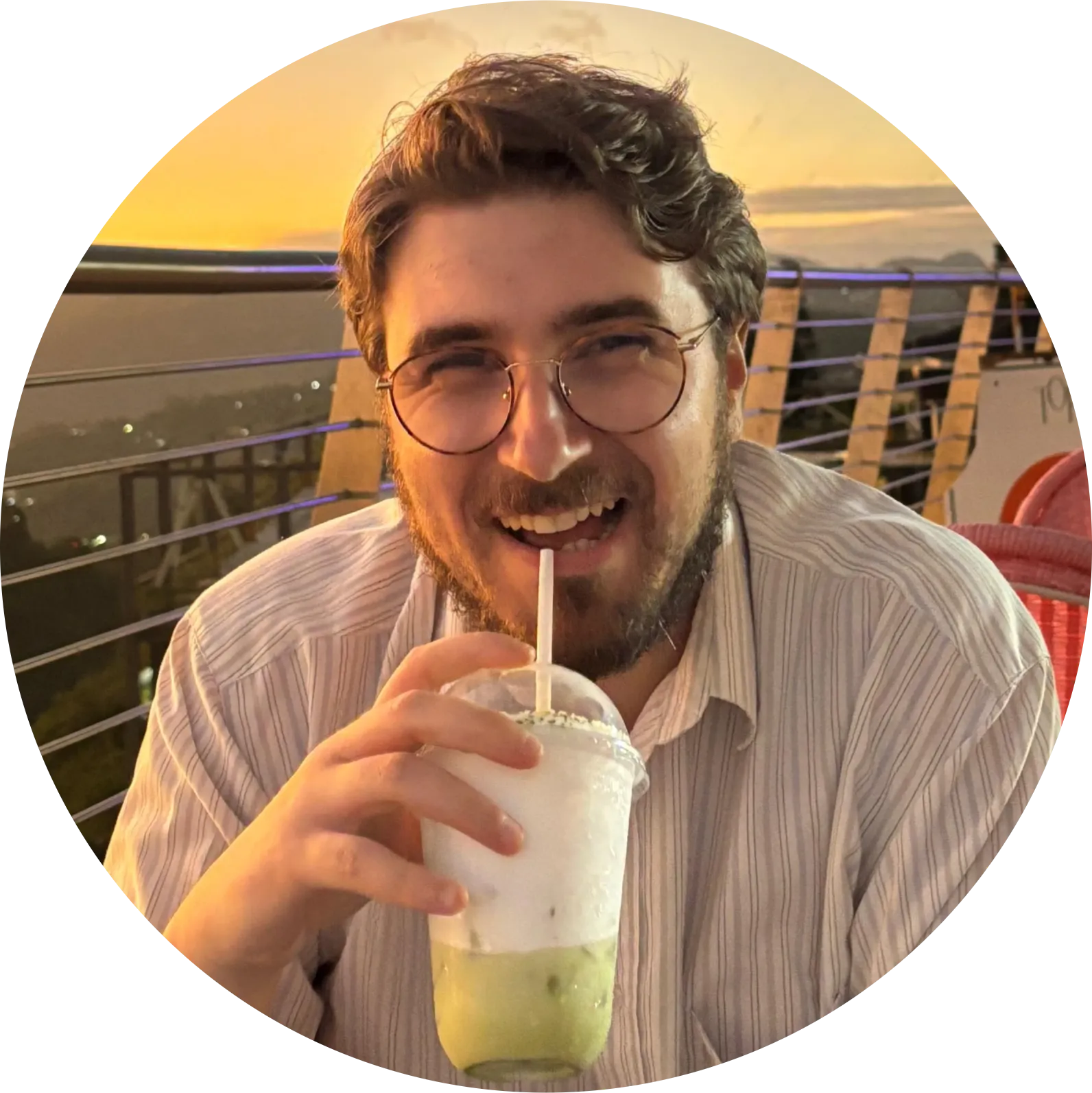 Alessandro smiling at sunset, holding an iced drink